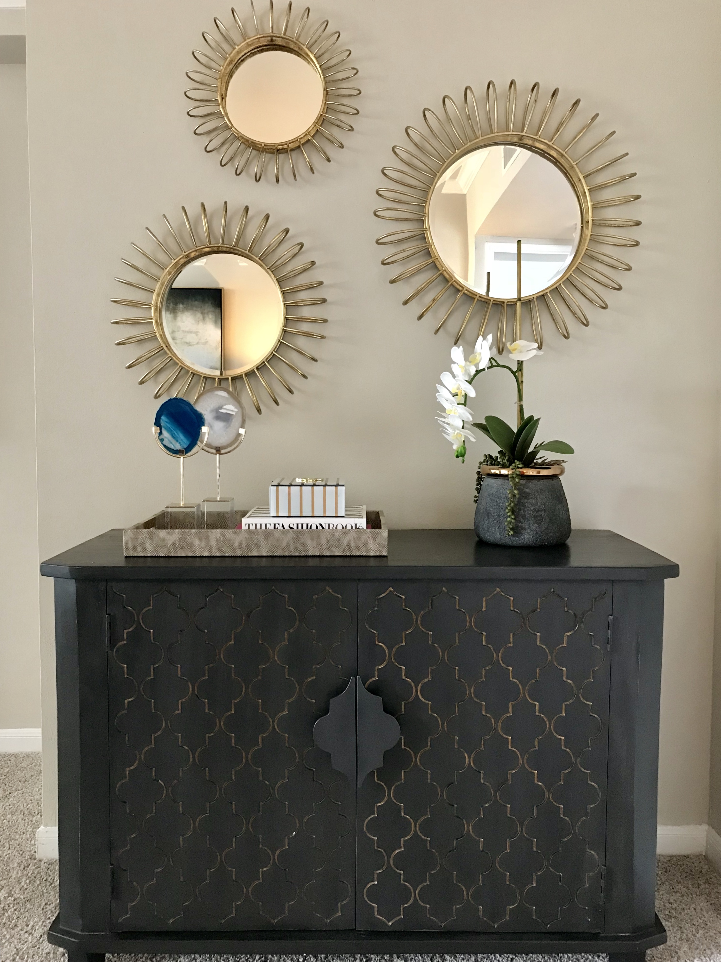 A black console table with gold accents, topped with decorative items