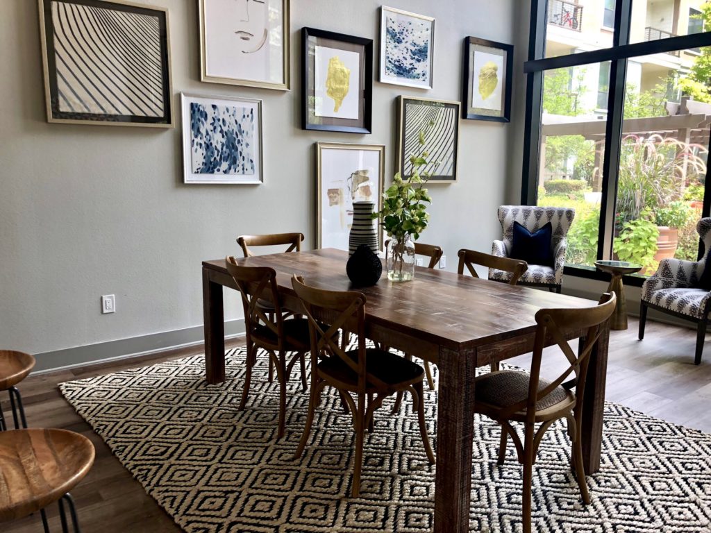 Dining room with a six chair long wooden table set and framed artworks for background