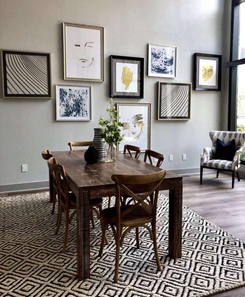 Dining room with a six chair long wooden table set and framed artworks for background