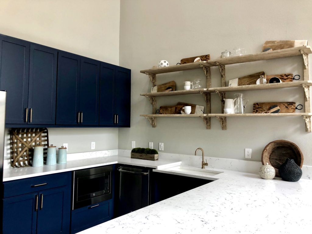 White kitchen sink and rustic wooden shelves with blue cabinets