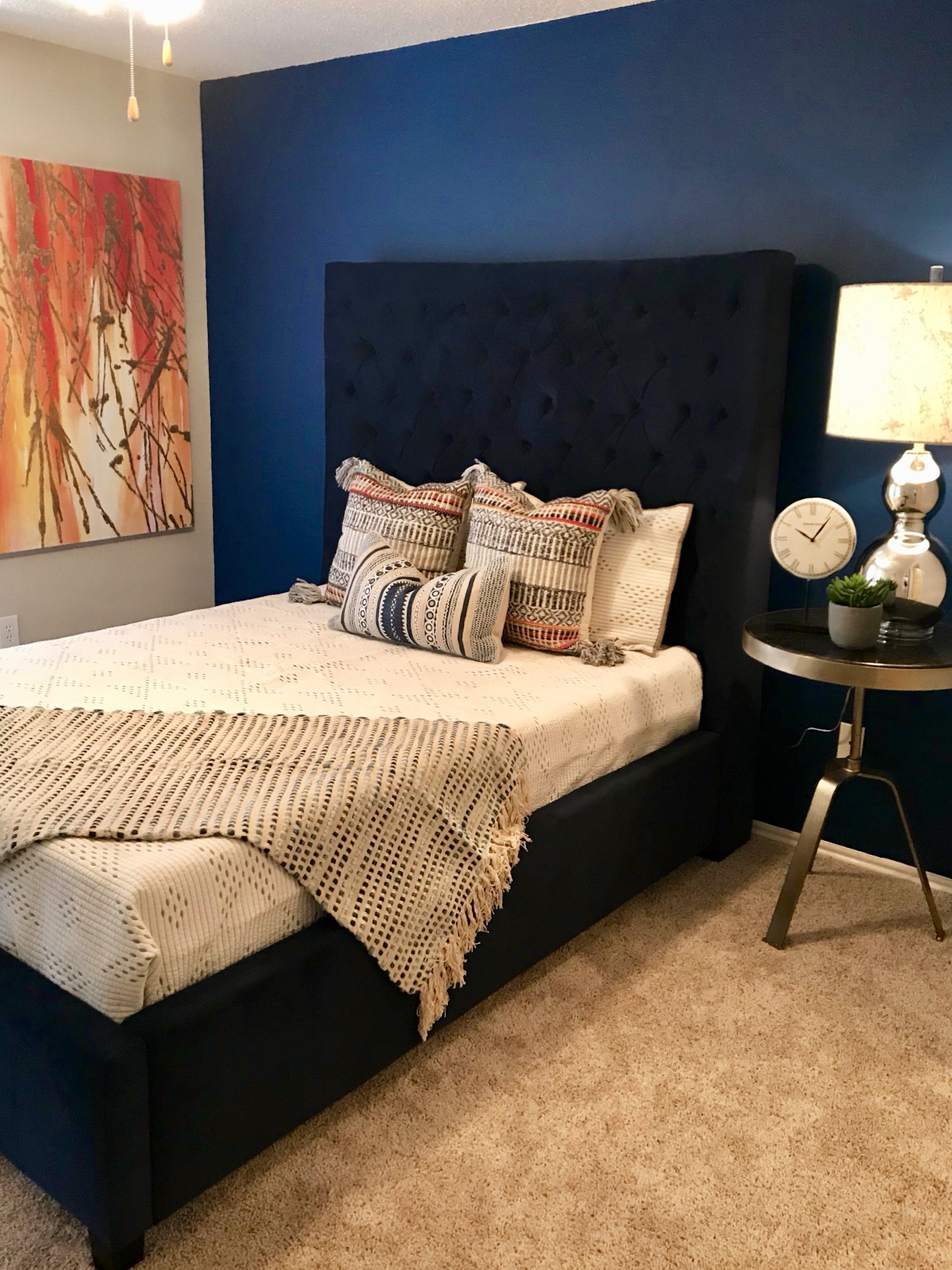 Bedroom with a dark blue bed, bedside table and light accents