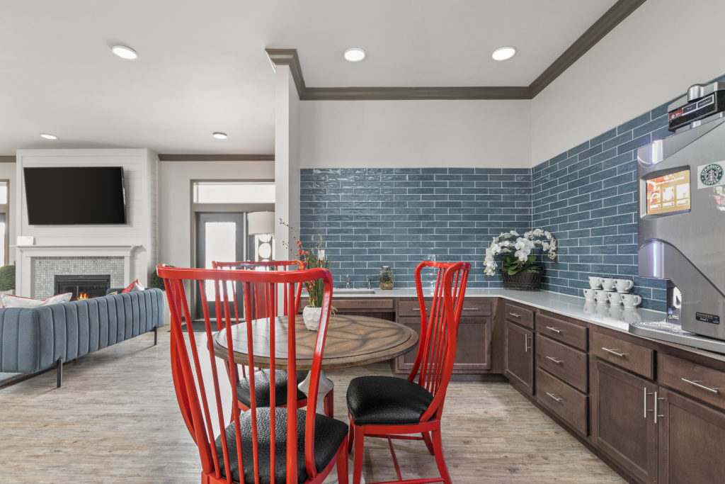 Clubroom transformation of the kitchen with blue subway tile as a backsplash and red dining chairs