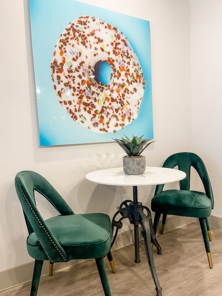 Dining room with green velvet chairs and donut artwork