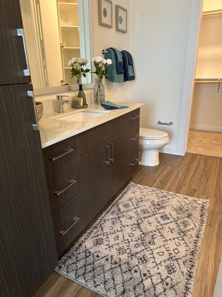 Bathroom of apartment stage with rug, towels and flowers