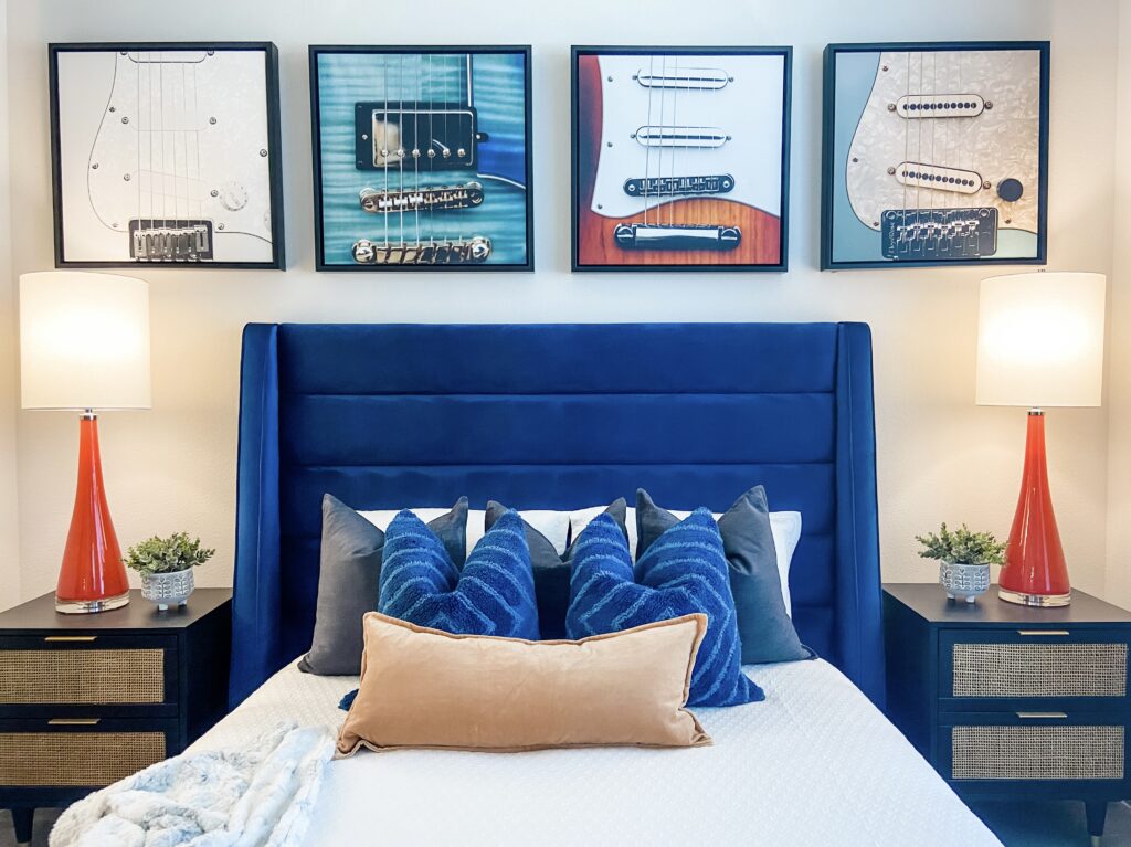 Unique guitar artwork and soft blue velvet headboard for this bedroom retreat