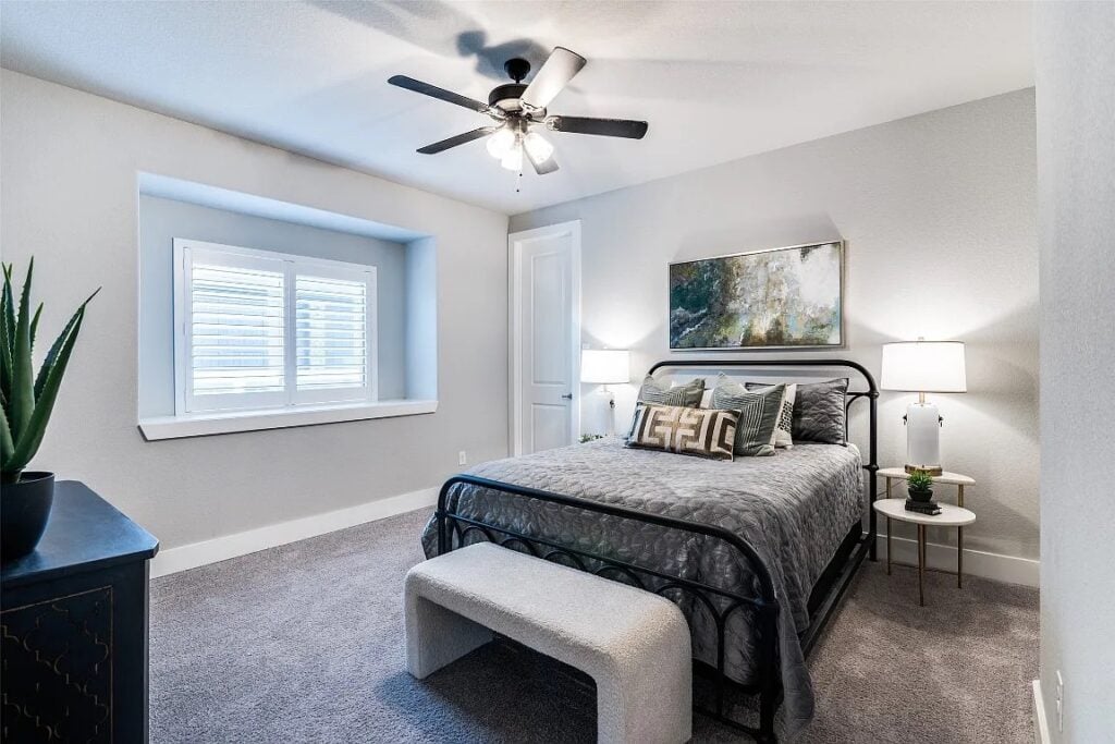 Home Stage of second bedroom with grey velvet bedding and black iron bed frame.