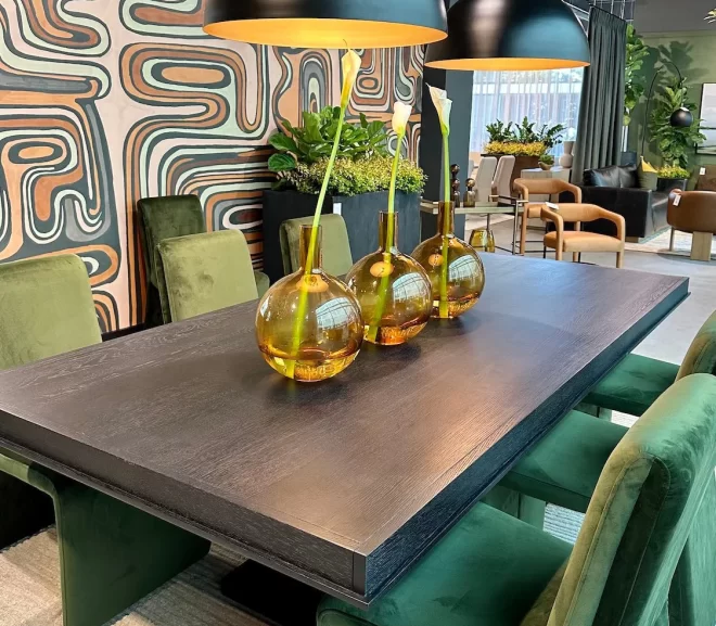 Dark wood dining table with green velvet chairs and large black pendant lights