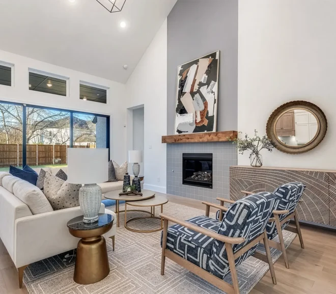Living room in Prosper Texas staged with a large grey and white geometric rug, two white sofas, two blue & white side chairs, gold side tables and coffee tables.