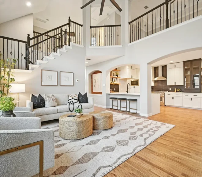 Staged living room in Dallas with large area rug, white sofa, white barrel chairs and bar area that opens to the kitchen