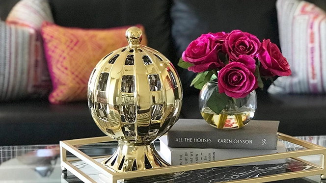 Golden globe and small red flower vase sitting on a coffee table