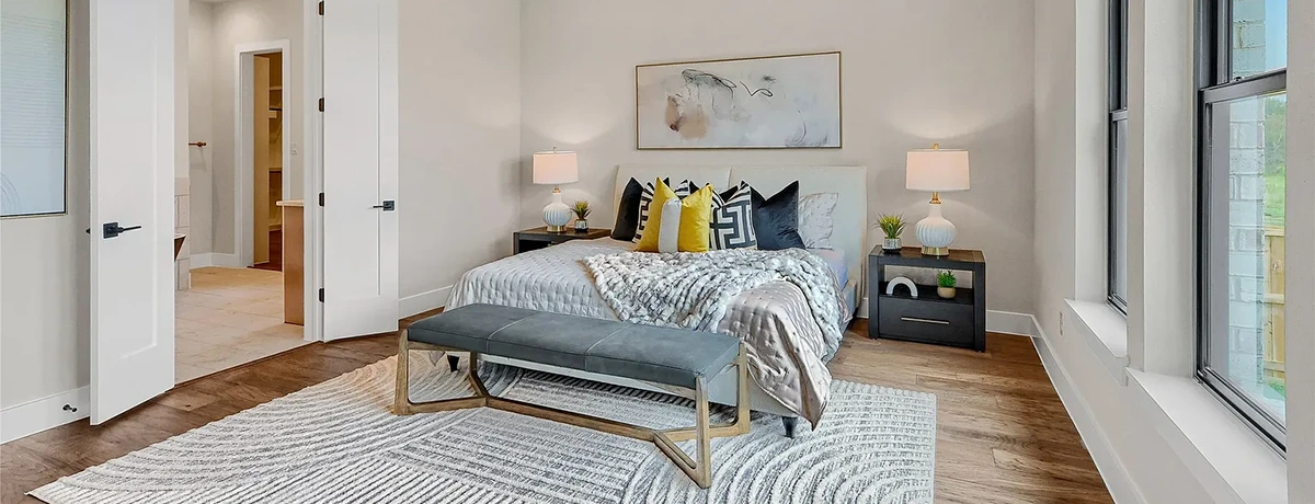 Bedroom with white headboard, black nightstands and grey leather bench