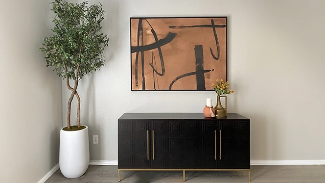 Black cabinet with gold trim and copper and black abstract artwork