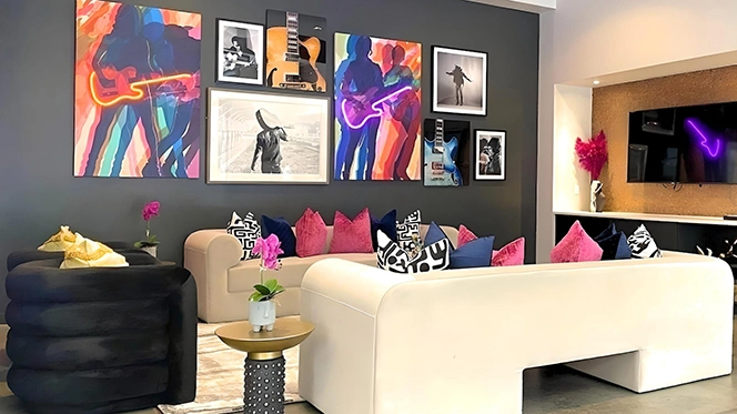 Vibrant clubroom with white sofas, pink pillows and neon lighted guitar artwork