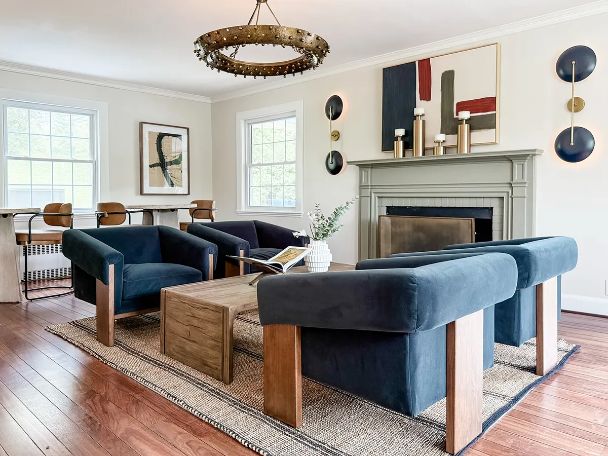 Leasing area with four modern velvet chairs, two tall round tables with leather high chairs and fireplace with abstract artwork