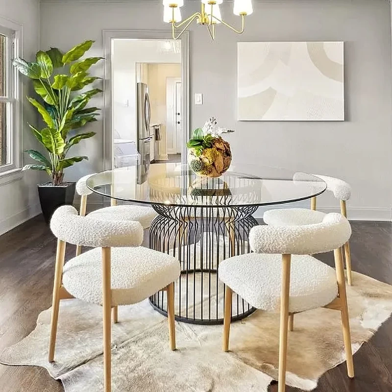 Dining room with round glass top table, four boucle chairs and cowhide rug