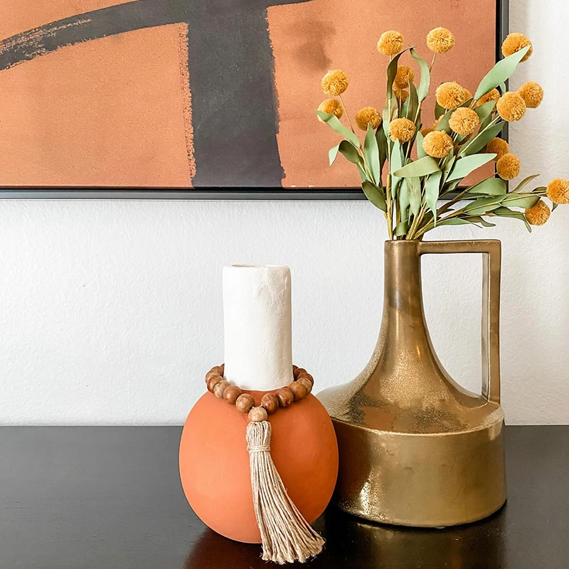Closeup of orange and gold home decor vases sitting on a dark wooden credenza