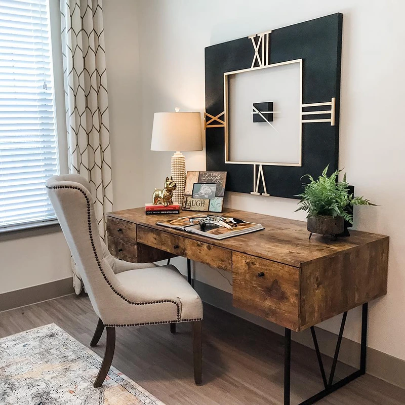 Home office desk with high back grey upholstered chair and large black square modern clock
