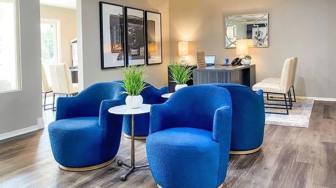 Reception area with four blue velvet round swivel chairs, grey l-shaped desk with two white guest chairs