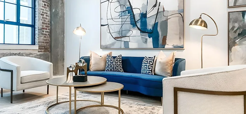 Elegant living room furniture with blue velvet sofa and two white chairs with gold accents