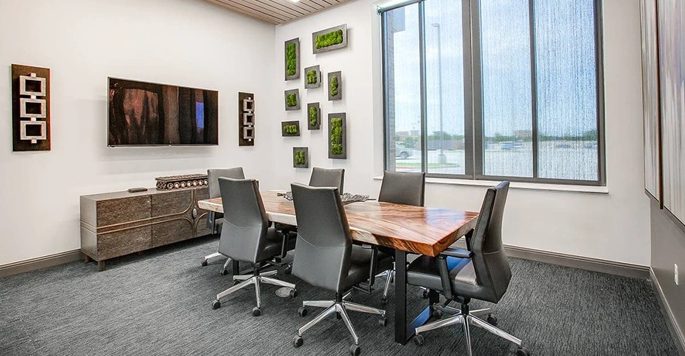 Conference room with large wooden table, grey high back leather chairs