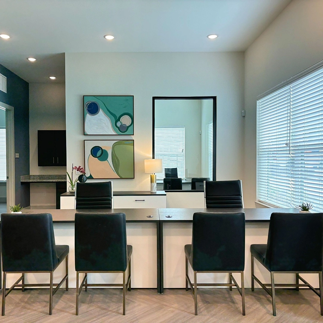 Office with two desks side by side with black modern executive chairs and four black guest chairs