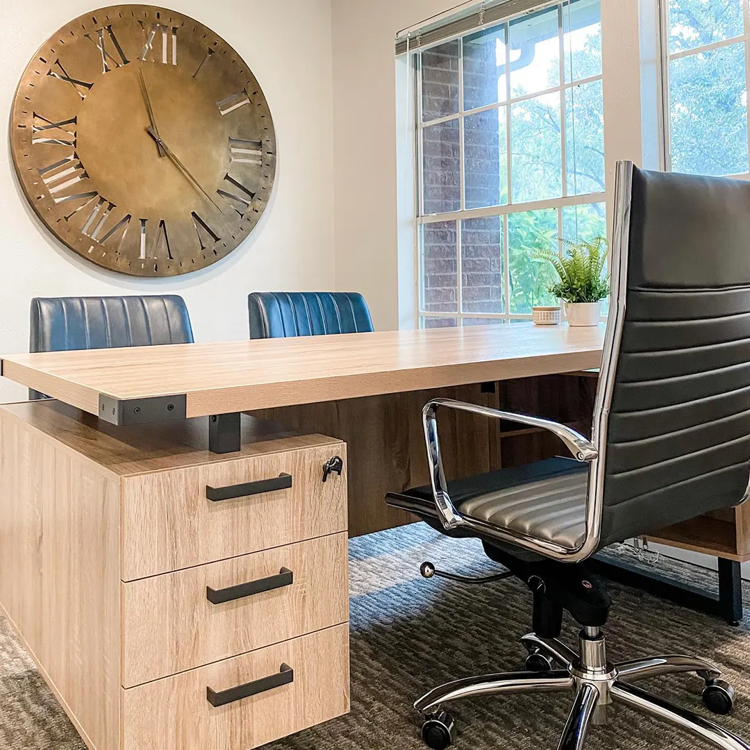 Light wood desk, black executive chair and copper wall clock