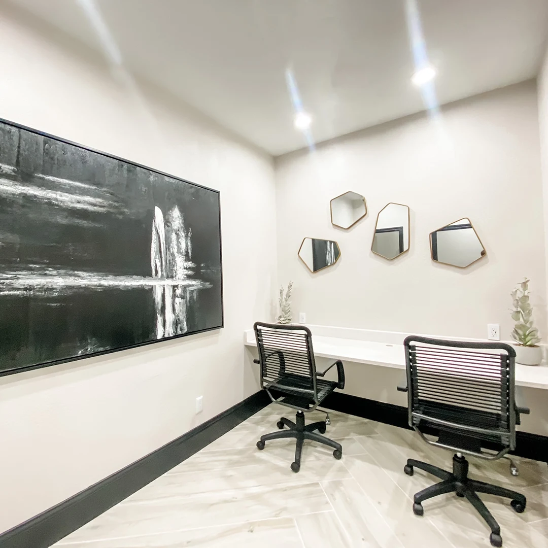 Business center with black mesh chairs, mirrors with gold borders and black and white artwork
