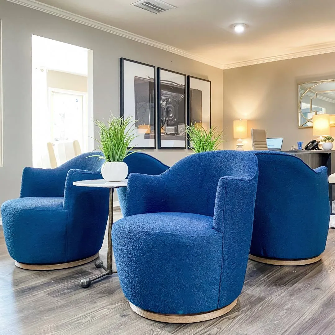 Leasing office seating with four blue boulce club chairs and photo of a old style camera in the background