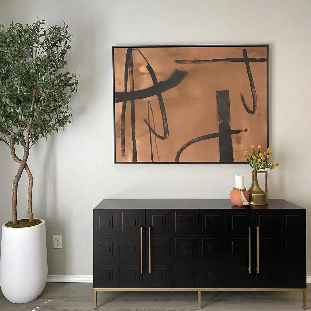 Black and gold console table, copper and black abstract artwork and faux greenery