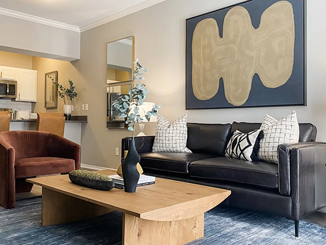 Living room with black leather sofa, burgundy chair and light wood coffee table