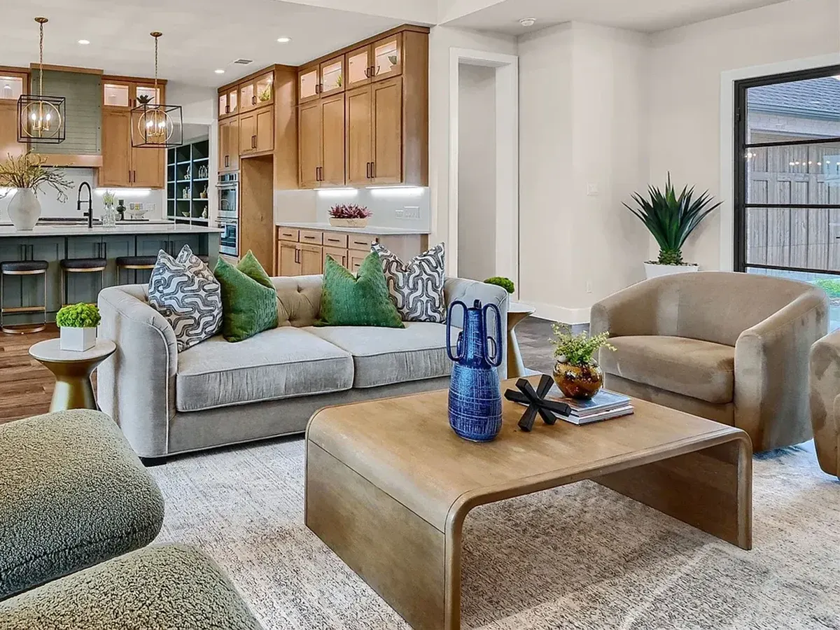 Living room with grey sofa and green pillows, tan suede side chairs