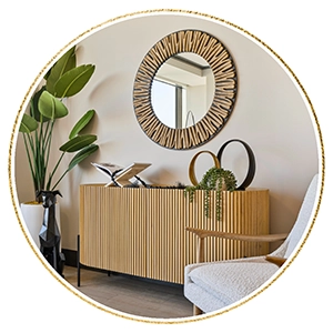 Light wood console table with round mirror, greenery and black dog statue