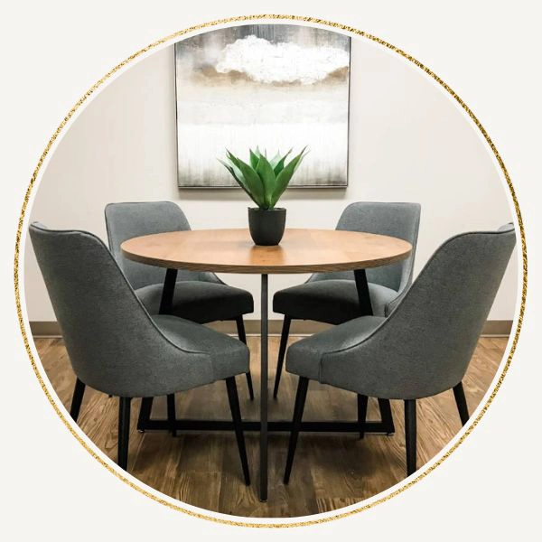 Round dining table with four dark grey leather chairs