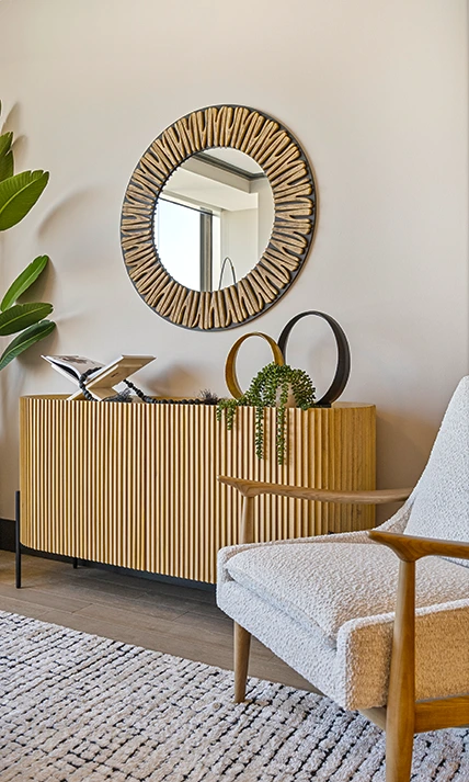 Wooden console table with large round mirror and white side chair