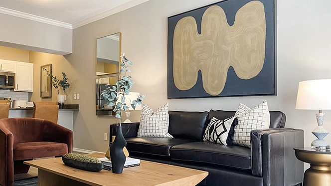 Modern living room with black leather sofa, burgundy chair, and large black & gold artwork